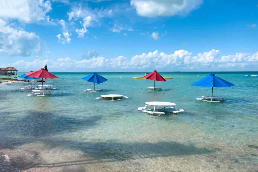 Picnic tables with umbrellas set in shallow ocean water at Chabil Mar Villas
