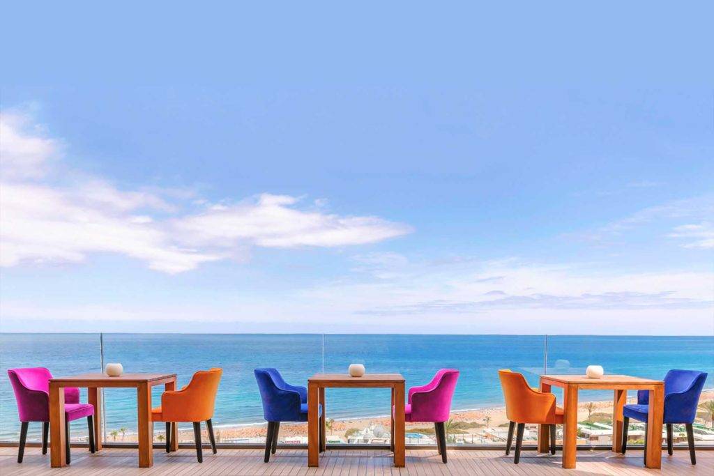 Terraza al aire libre con mesas y sillas con vista al mar | Bohemia Suites & Spa