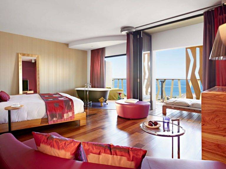 Corner Junior Suite: habitación moderna de estilo bohemio con cama King, sala de estar, bañera con patas y balcón con vista al mar | Bohemia Suites & Spa