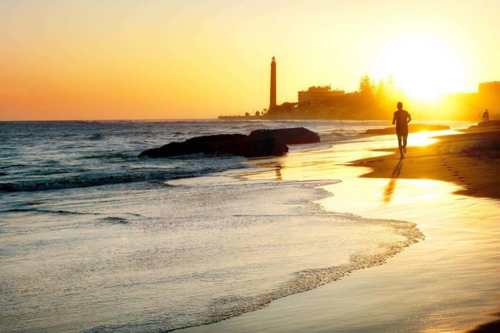 Mann, der bei Sonnenuntergang auf Gran Canaria an einem Strand entlang läuft