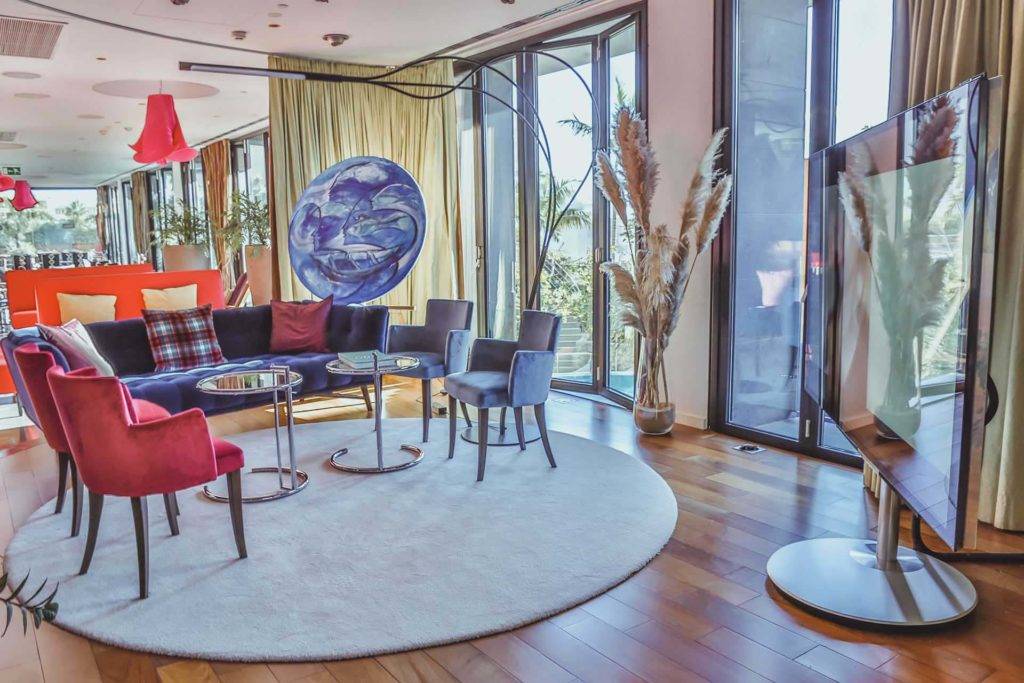Lounge-Sitzbereich mit Blick auf einen großen Fernseher in der Lobby des Bohemia Suites & Spa