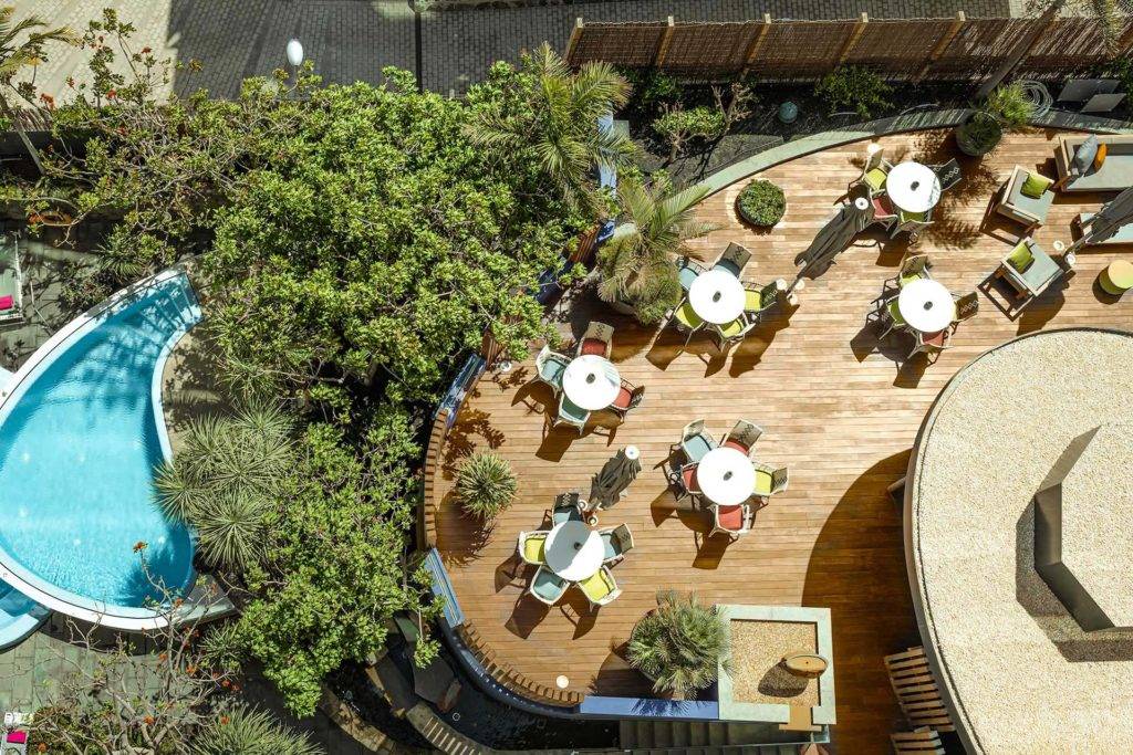Vista aérea de la terraza exterior del Pool Bar con mesas y sillas en Bohemia Suites & Spa
