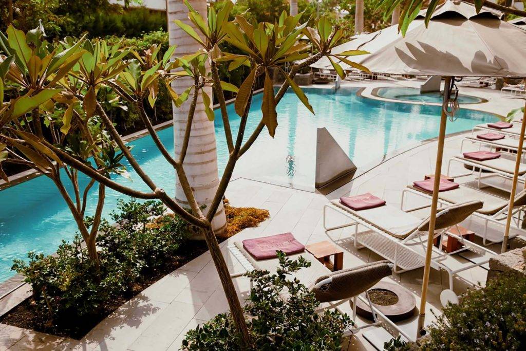 Außenpool und Whirlpool umgeben von Liegestühlen, Sonnenschirmen und üppigem Grün im Bohemia Suites & Spa