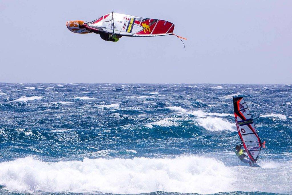 Windsurfistas haciendo trucos sobre las olas del mar frente a la isla de Gran Canaria