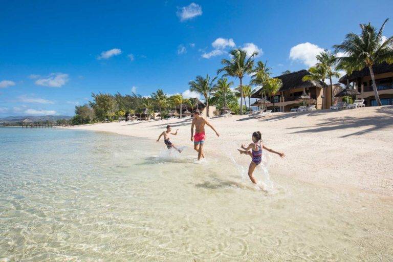 Familia jugando y chapoteando en la playa en Shanti Maurice Resort & Spa