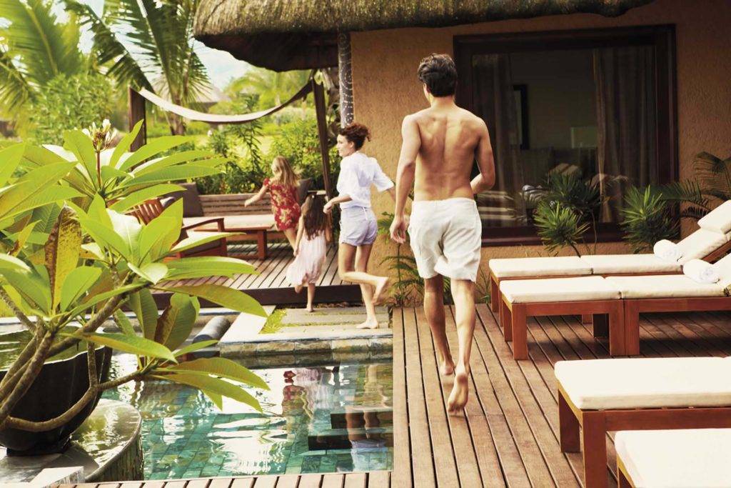 Familia de cuatro personas caminando por la terraza de su villa privada en Shanti Maurice Resort & Spa