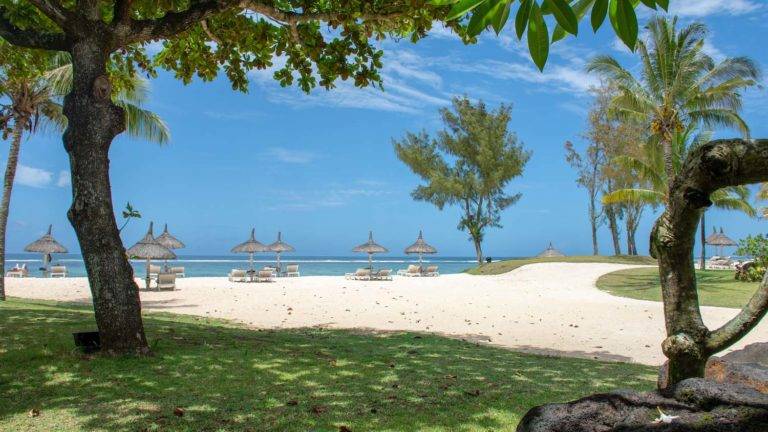 Suite Junior con vista a la laguna - Vista de la playa del océano con sillones y sombrillas con techo de paja | Shanti Maurice Resort & Spa