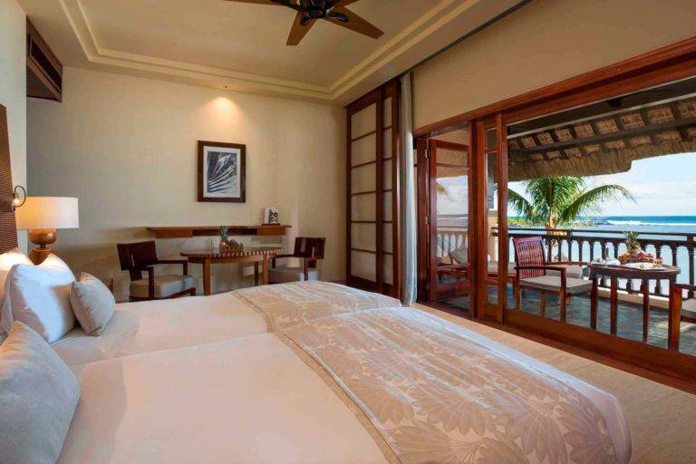 Suite Junior frente al mar: dormitorio doble con dos camas individuales, pequeña mesa de comedor y puertas que dan al balcón exterior | Shanti Maurice Resort & Spa