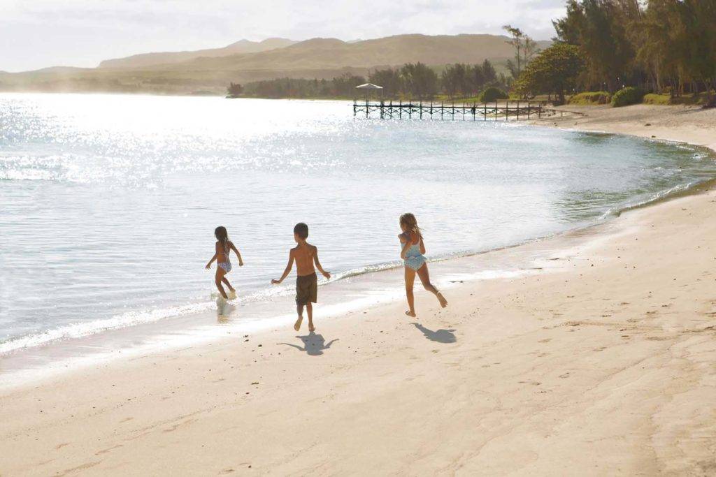 Niños corriendo hacia el agua en la playa de Shanti Maurice Resort & Spa