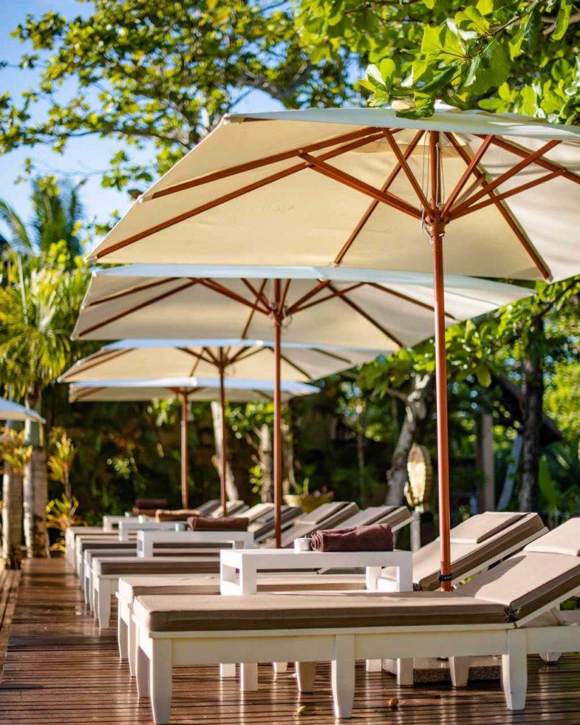 Tumbonas cubiertas con sombrillas junto a la piscina en Shanti Maurice Resort & Spa