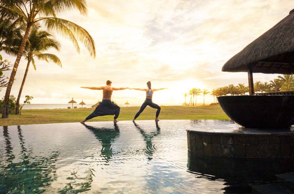 Pareja haciendo yoga al borde de la piscina infinita en el Spa en Shanti Maurice Resort