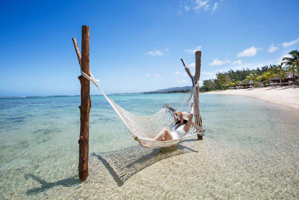 Mujer relajándose en una hamaca de playa sobre el agua en el Shanti Maurice Resort & Spa