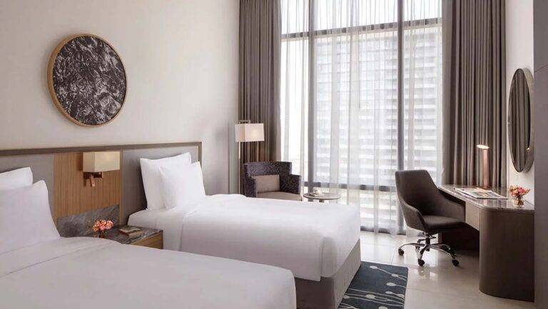 Classic Room - contemporary room with twin beds, sitting area, workstation and large windows | First Collection Hotel at JVC