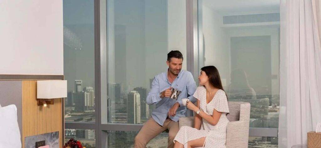 Couple drinking coffee in their First Collection JVC Hotel room