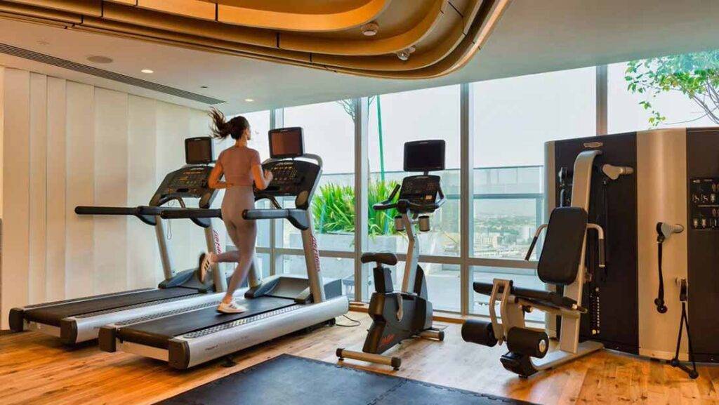 Woman jogging on a treadmill in the First Collection JVC Hotel fitness center