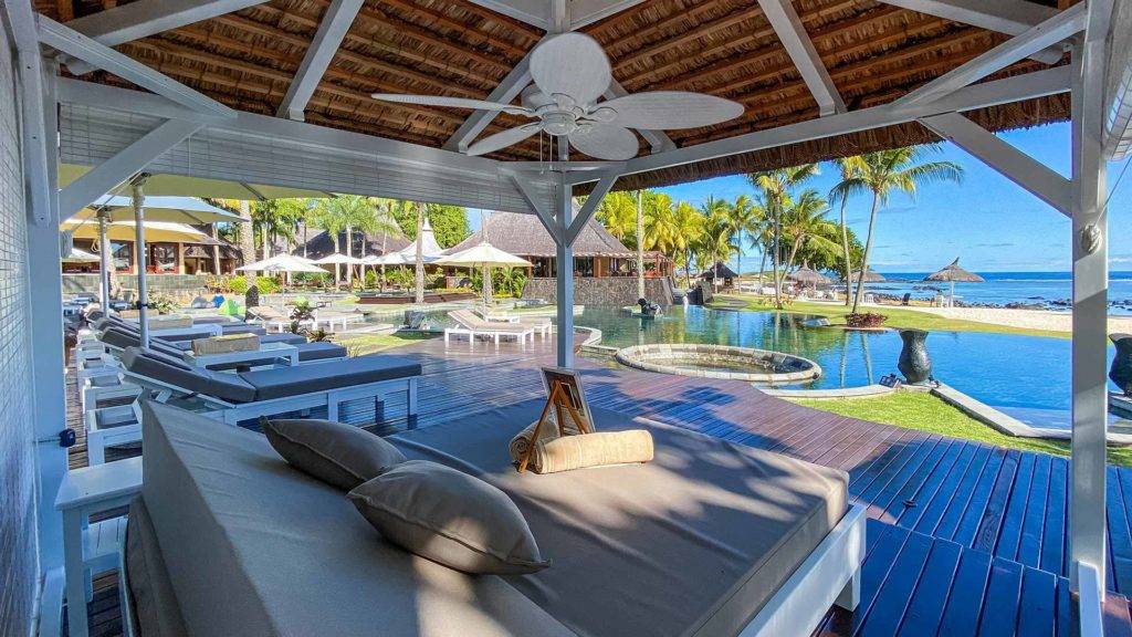 Shanti Maurice Resort 的私人小屋配有沙发床和躺椅，可俯瞰度假村游泳池