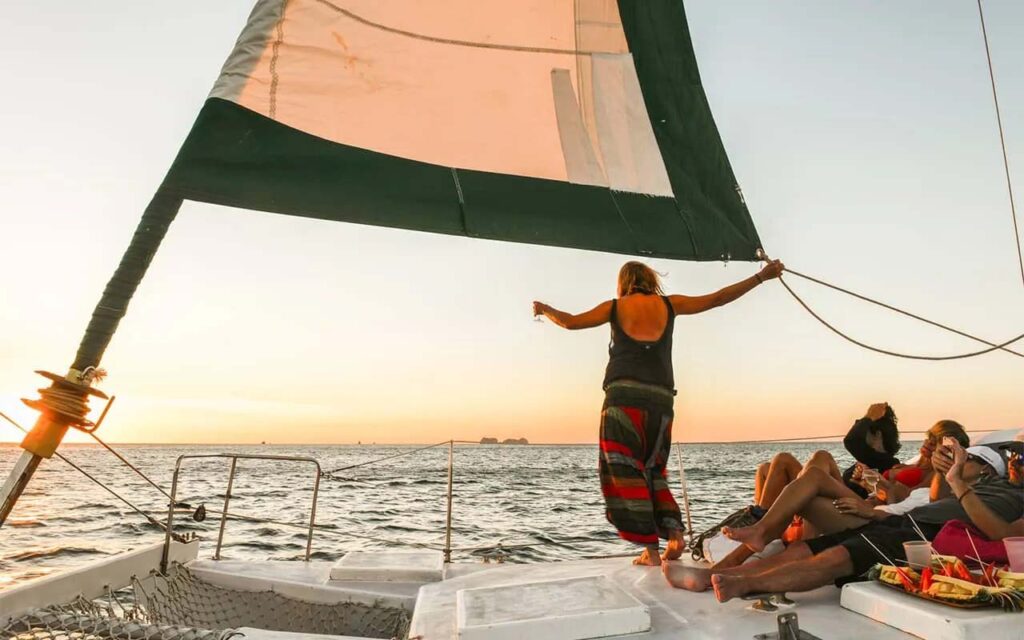 Grupo de personas en un catamarán viendo la puesta de sol sobre el océano en Costa Rica