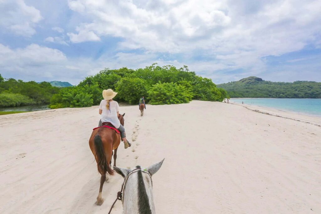 Grupo de personas montando a caballo en una playa de Costa Rica