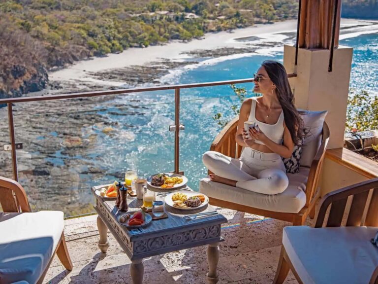 Mujer disfrutando del desayuno en el balcón de su villa privada con vista al mar | Casa Camaleón en Las Catalinas