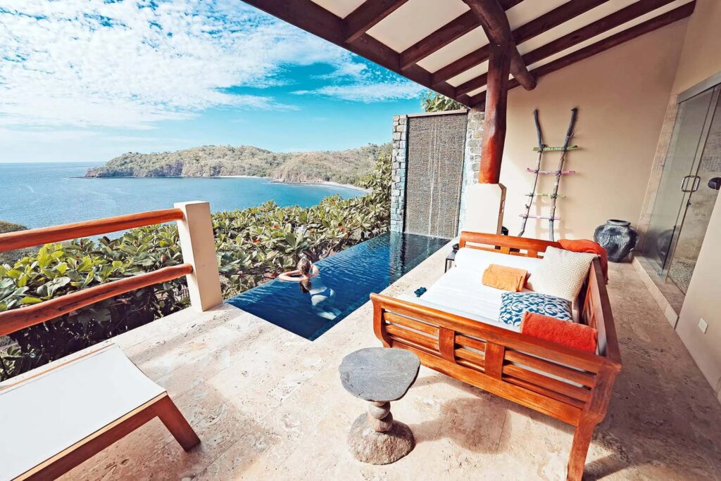 Villa con piscina de inmersión: Balcón con muebles lounge y mujer en la piscina de inmersión con vistas al océano | Casa Camaleón en Las Catalinas