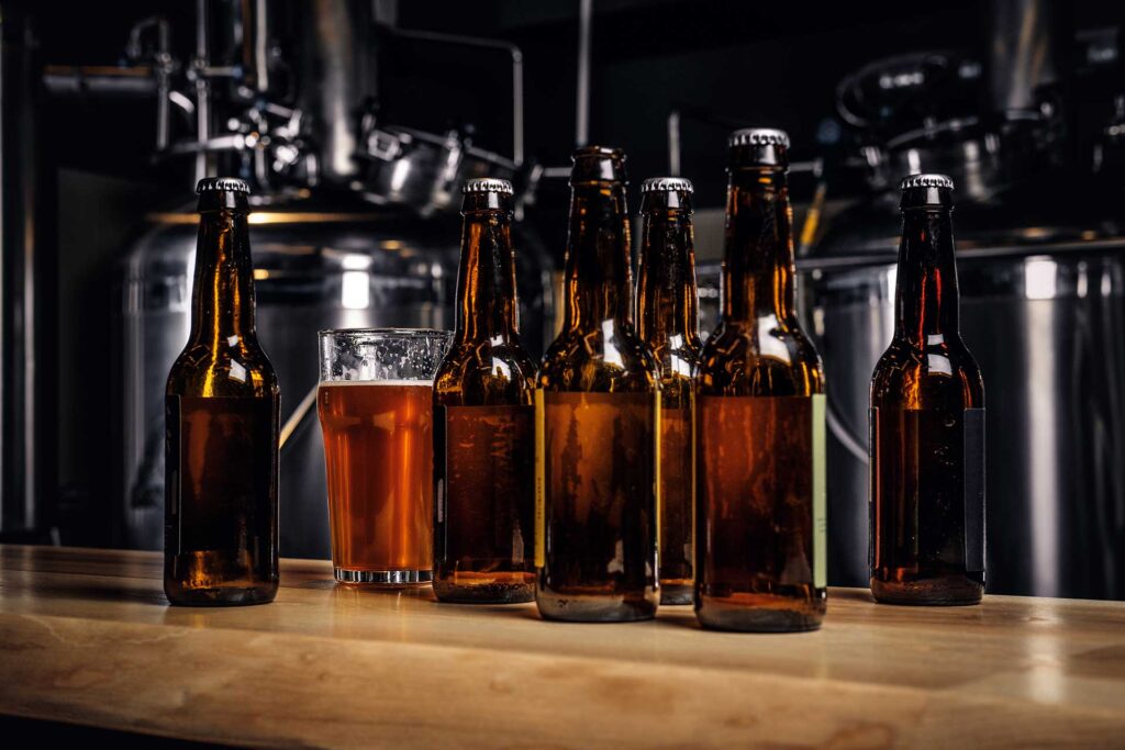 Botellas de cerveza artesanal colocadas sobre una barra de madera en una cervecería