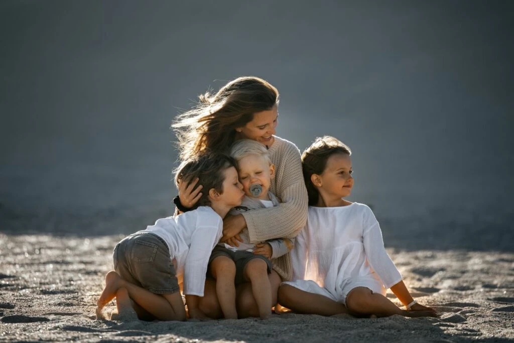 Mutter und drei Kinder genießen ihre gemeinsame Zeit am Strand bei Sonnenuntergang