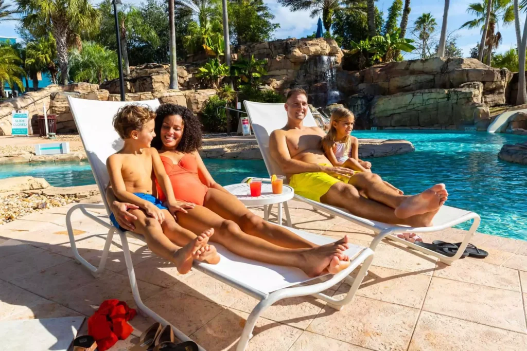 一家人坐在躺椅上，在 Spectrum Resort 水上乐园晒太阳放松