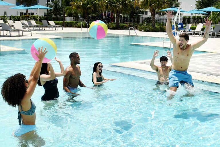Eine Gruppe von Freunden spielt mit Wasserbällen im Pool des Spectrum Resort Clubhauses