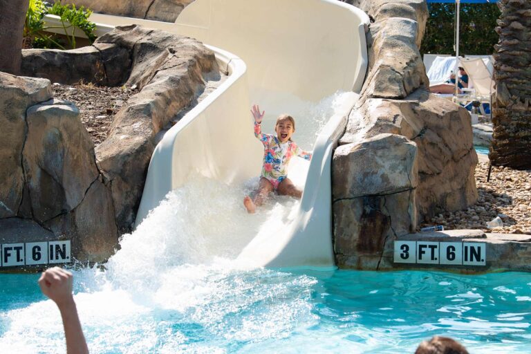 Junges Mädchen rutscht die Wasserrutsche im Wasserpark im Reunion Resort hinunter