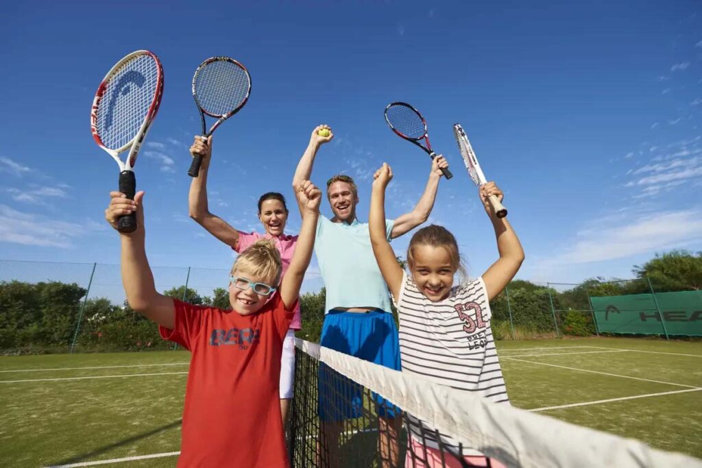 Familia feliz emocionada de jugar tenis en la cancha de Martinhal Sagres