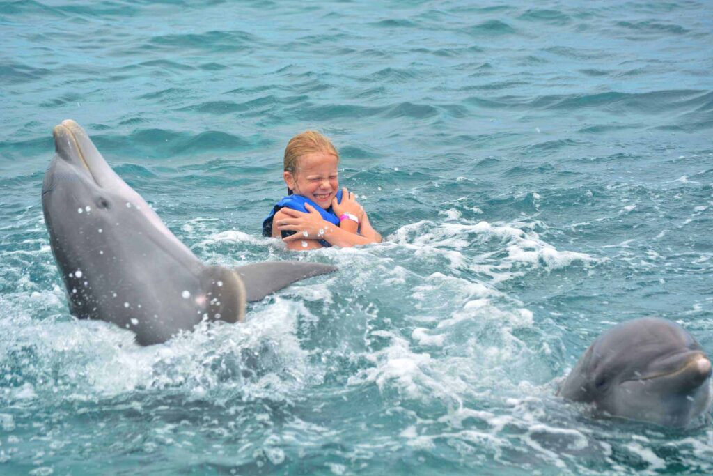Niña nadando con delfines