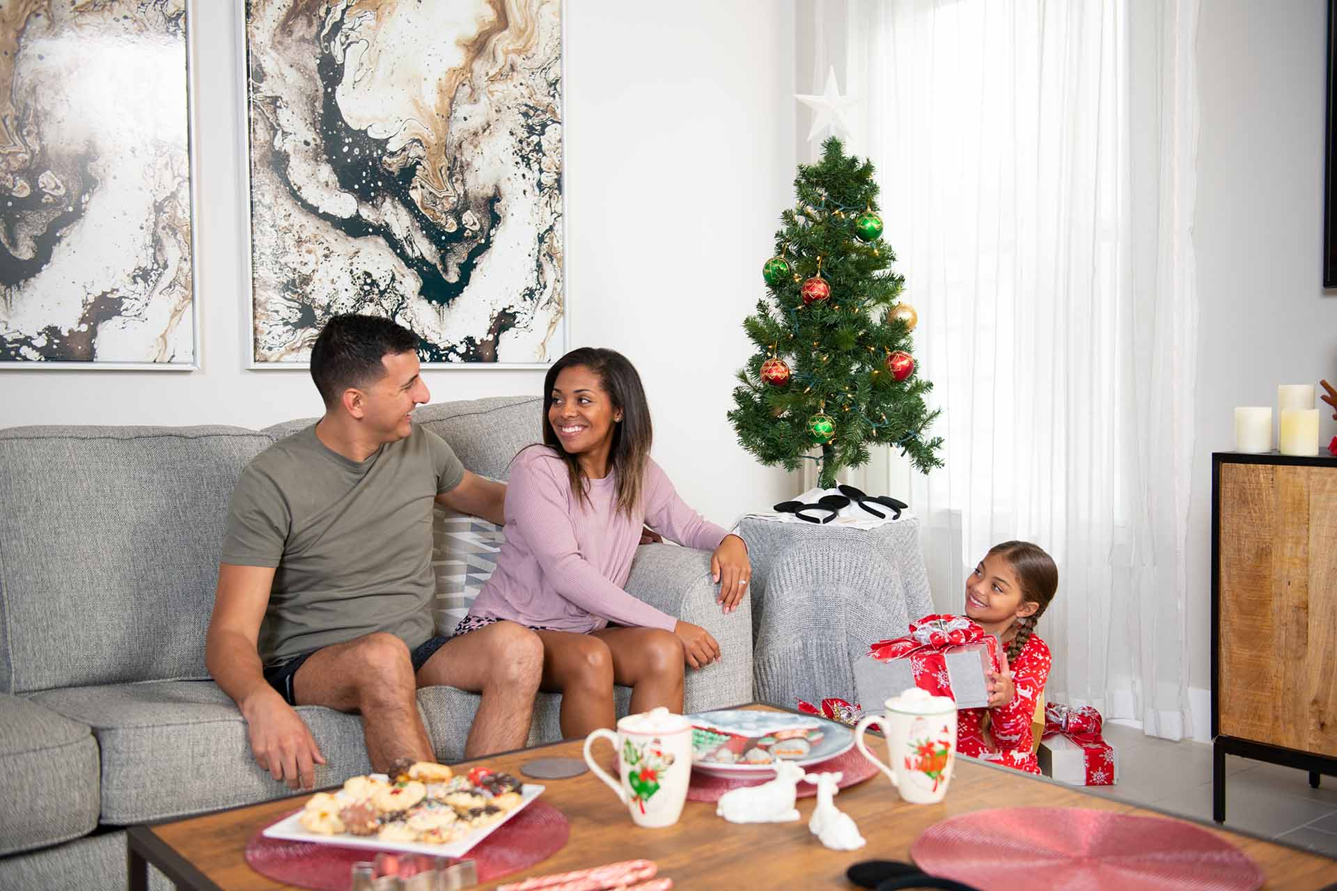 Familia celebrando la mañana de Navidad en la sala de estar de su casa en Bear's Den Resort