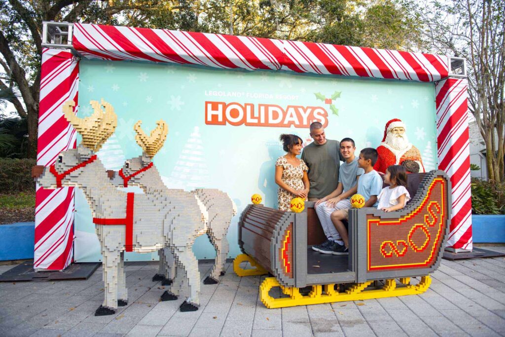 Familia tomándose una foto en el trineo de Papá Noel hecho con Legos