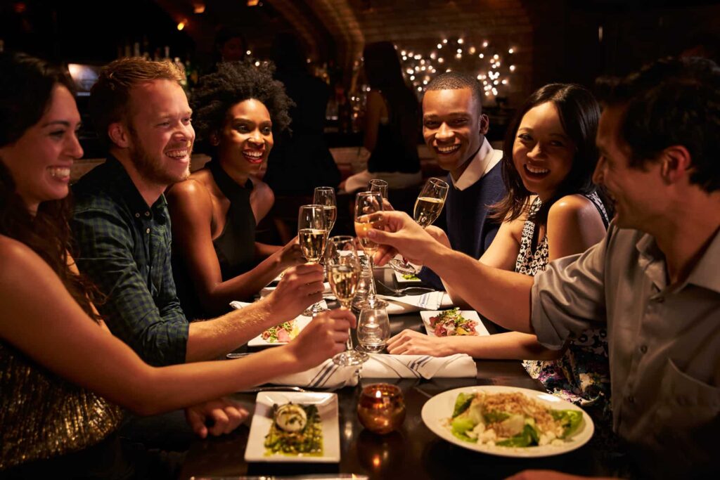 Group dining at a restaurant raising glasses of champagne in a toast