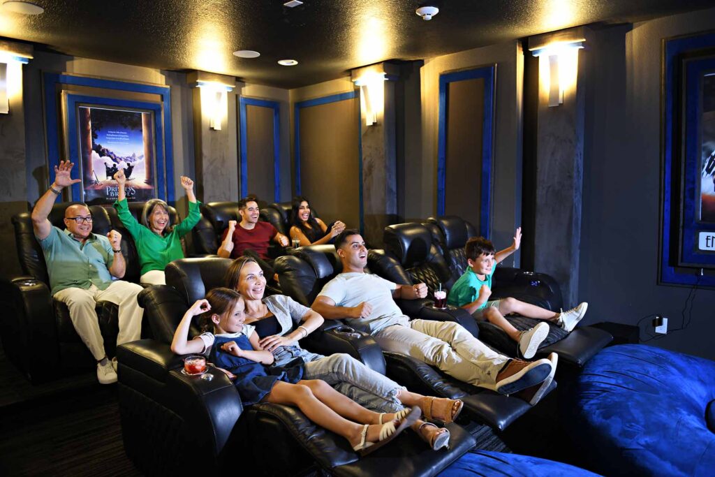 Family enjoying watching the big screen in their private movie theater room at Encore Resort